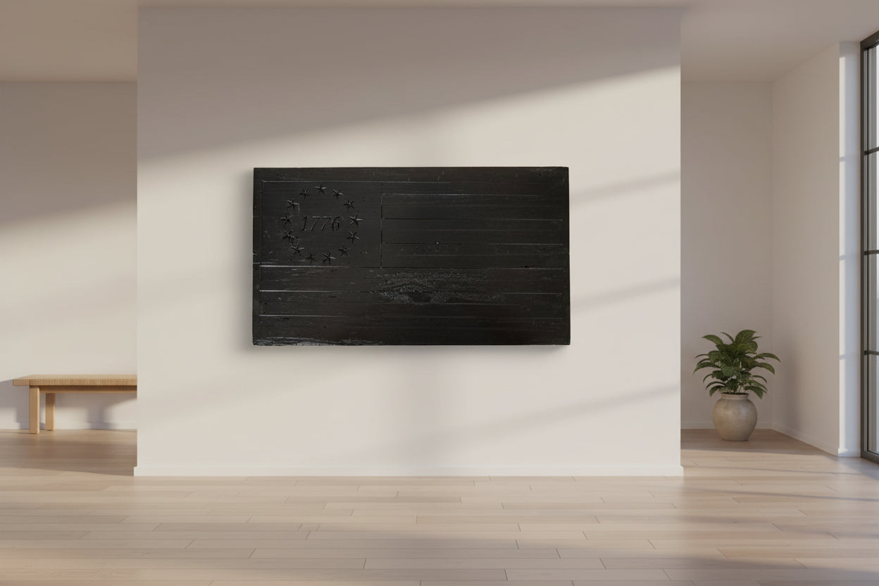 Black wooden plaque with American flag design and '1776' on a light wood surface.
